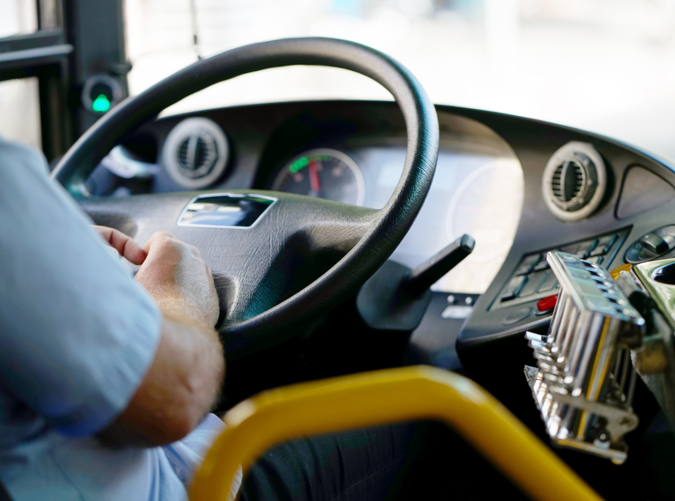 close up of a bus driver's hands on the steering wheel