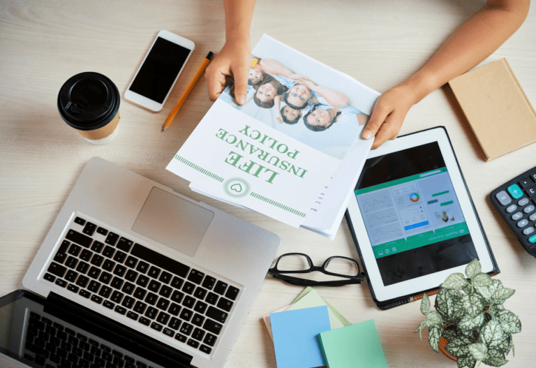 photo of a person holding a brochure for life insurance in front of a laptop and tablet