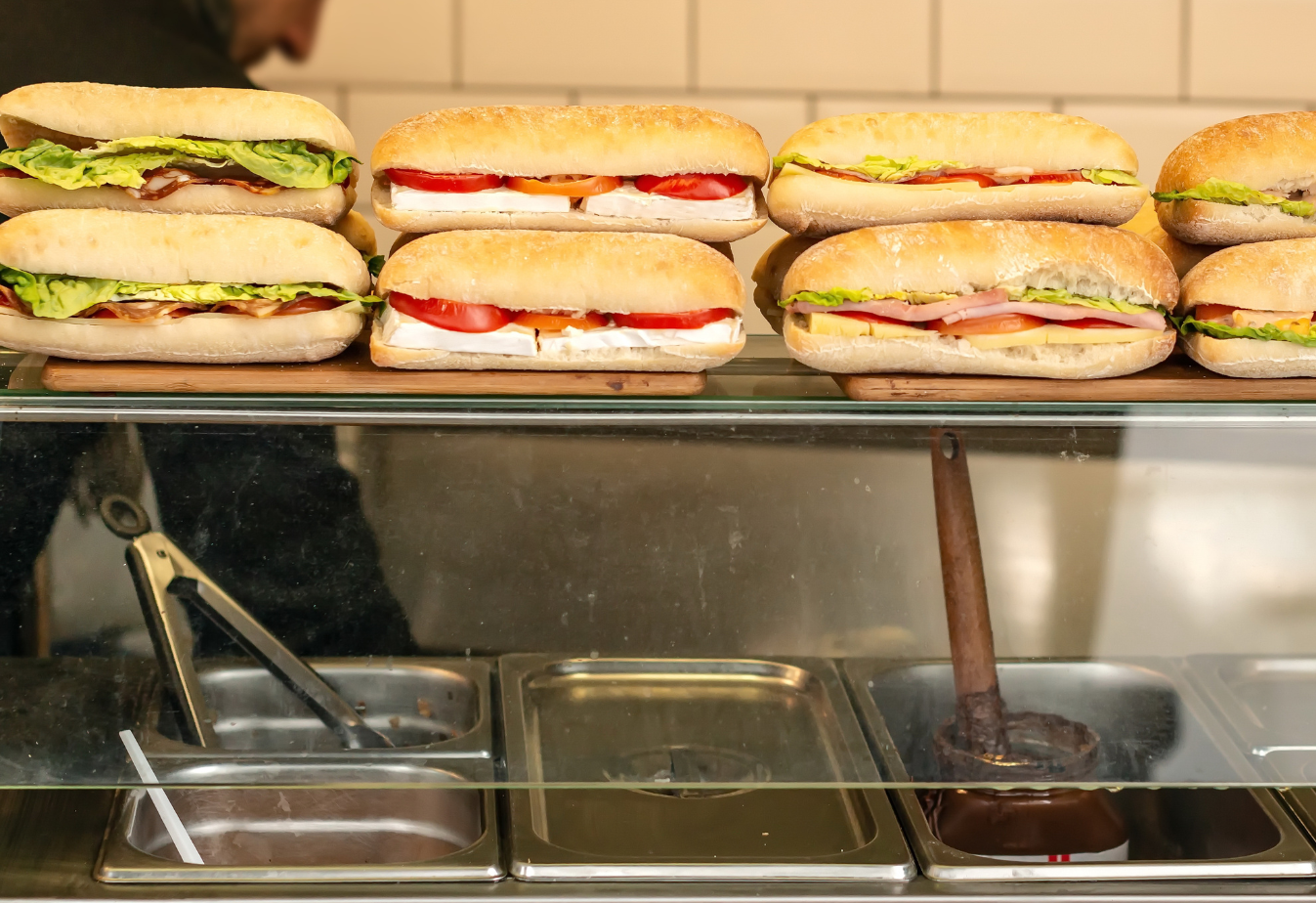 stacked sub sandwiches on top of a fast food counter