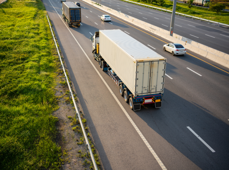 a tractor-trailer truck on a highway next to a car