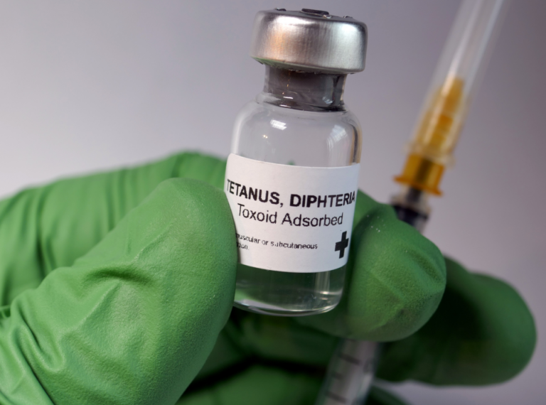 a vial of the tetanus vaccine held in a green glove