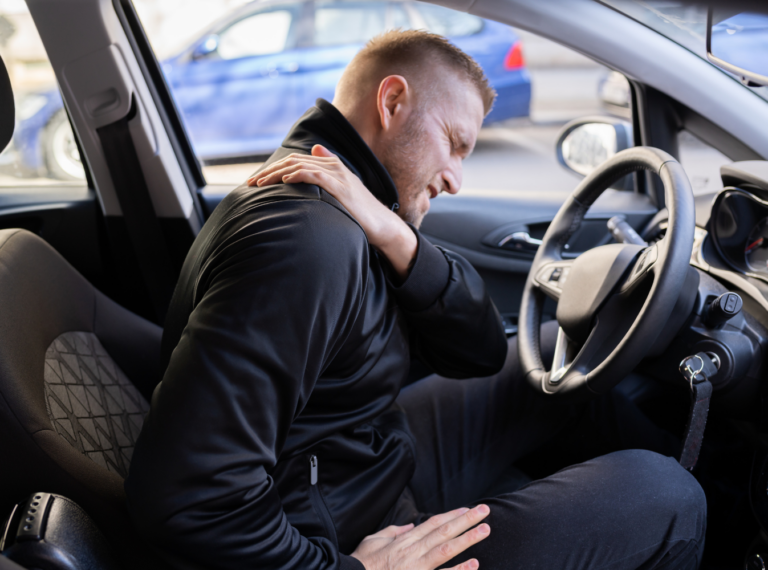 a driver holding his shoulder indicating back pain