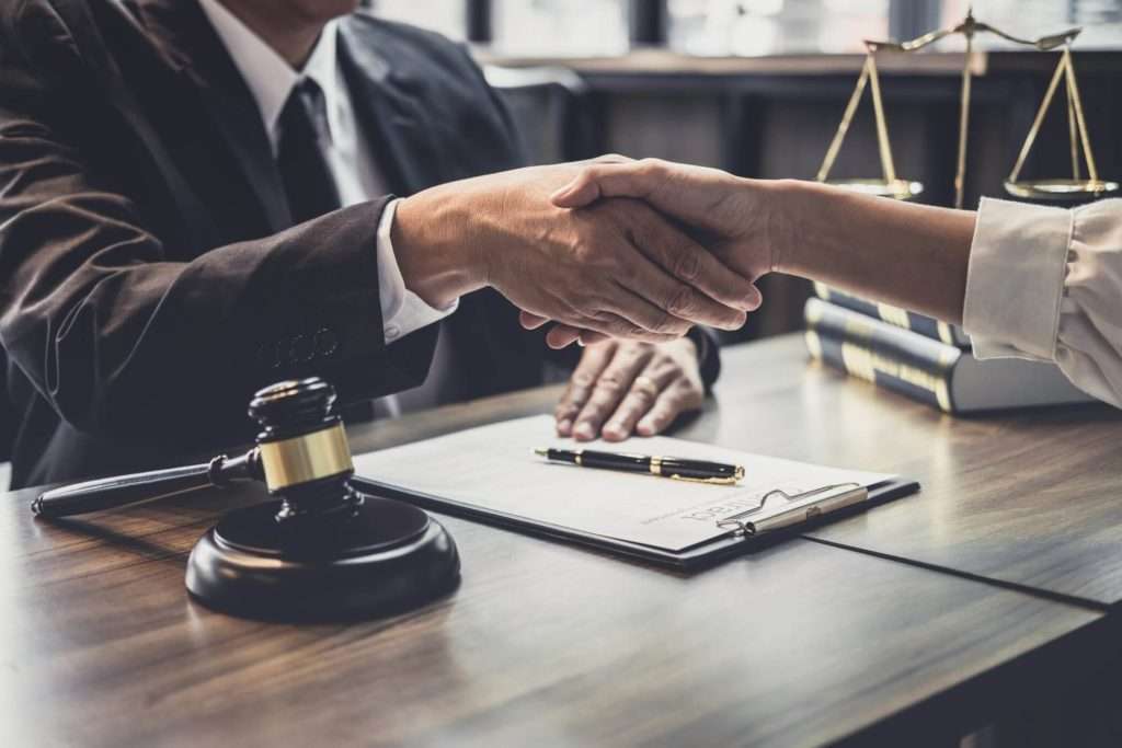two people shaking hands over a desk with a gavel on it