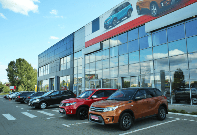 outside a car dealership with orange and red suvs parked out front