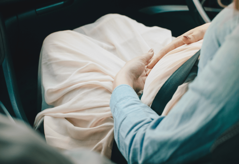 a pregnant woman buckled in to the passenger side seat of a car