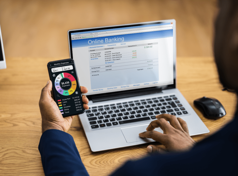 someone using a phone and laptop to look at online banking account