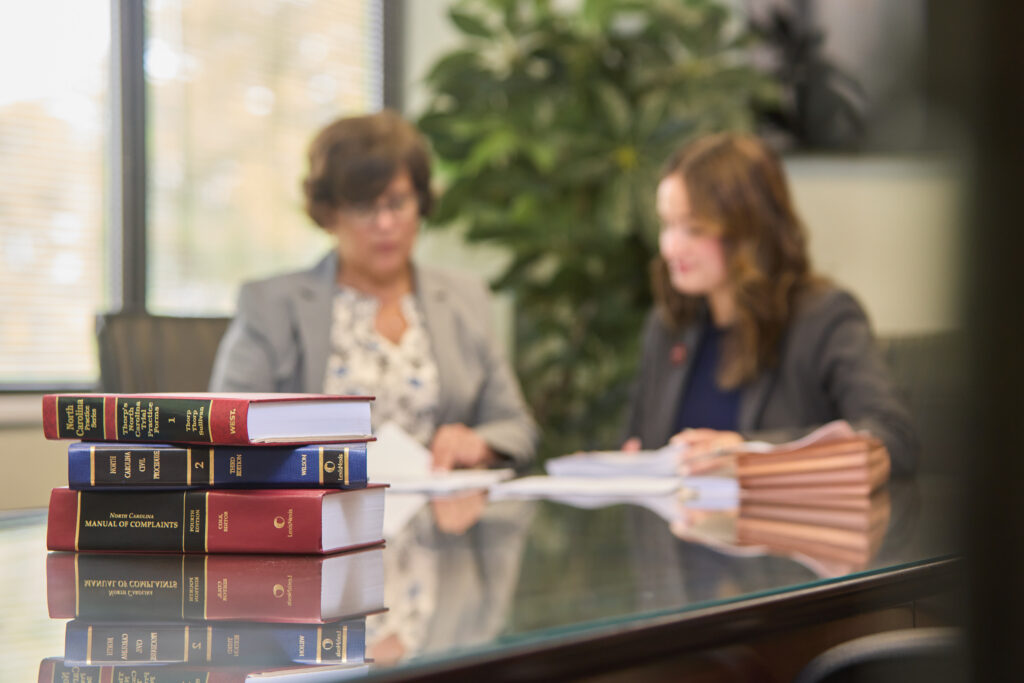 books in the forefront, two people looking over a document in the background